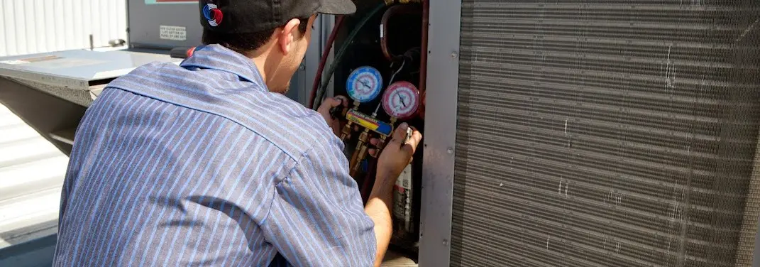 HVAC technician servicing a condenser unit in Pavilion
